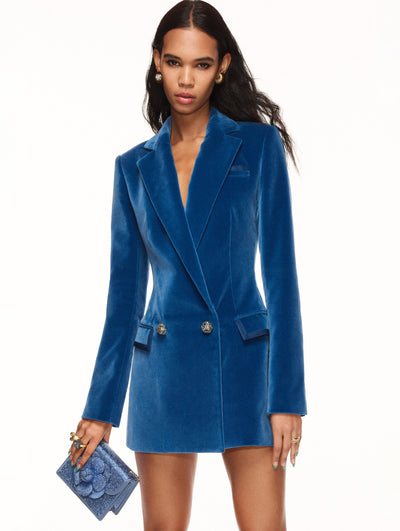 A model poses against a white backdrop in an Oscar de la Renta blue velvet blazer dress.