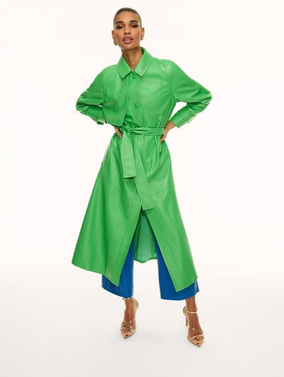 A model poses against a white backdrop in an Oscar de la Renta green leather trench coat. 