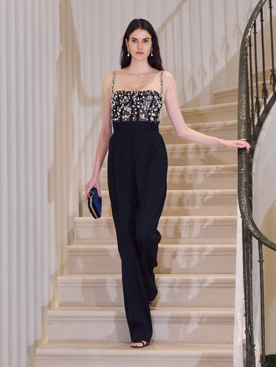 The model wears a black jumpsuit with crystal embroidery at the bustier.  