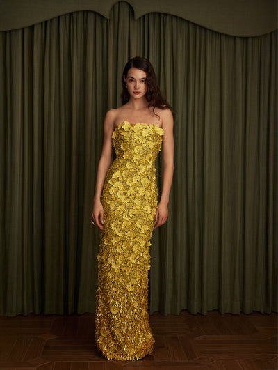 The model wears a yellow flower embroidered strapless gown.  