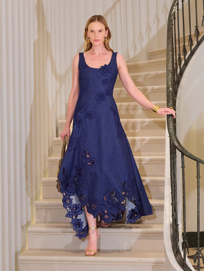 The model is wearing a dark denim midi dress with floral embroidery.  