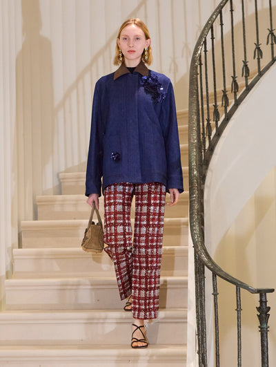 The model is wearing a dark denim jacket and plaid pants. The styles feature floral embroidery.  