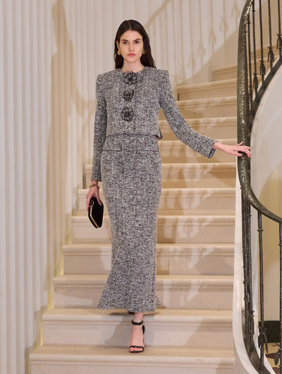 The model is wearing a grey plaid jacket and maxi skirt set. The styles feature floral embroidery.  