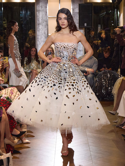 The model wears a statement strapless cocktail dress with feather detailing.  
