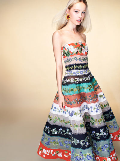 The model is wearing a strapless midi dress with striped, floral detailing. 
