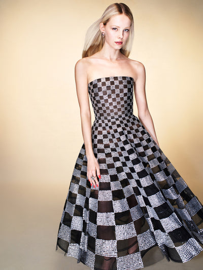 The model is wearing a strapless black and silver checkered evening gown. 