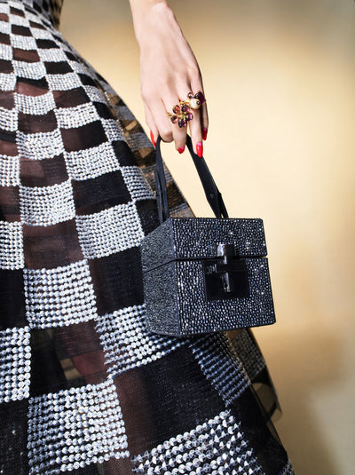The model is carrying a black sequin box shaped handbag with a black and silver checkered evening dress. 