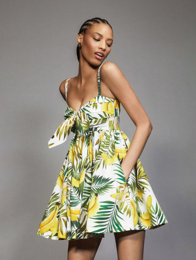 A model poses against a grey backdrop in an Oscar de la Renta banana printed mini day dress. 