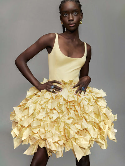 A model poses against a grey backdrop in an Oscar de la Renta yellow cocktail dress.