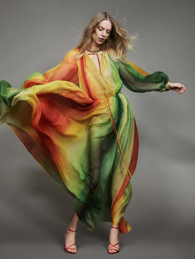 A model poses against a grey backdrop in an Oscar de la Renta abstract long-sleeve maxi dress.