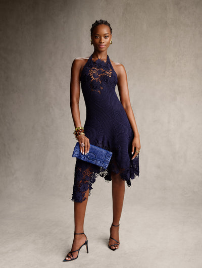 The model is wearing a navy crochet halter-neck dress. 