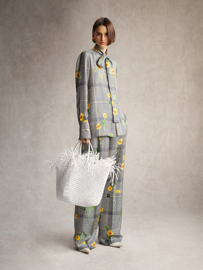 The model is wearing a black and white plaid shirt and pant with yellow flowers throughout. 