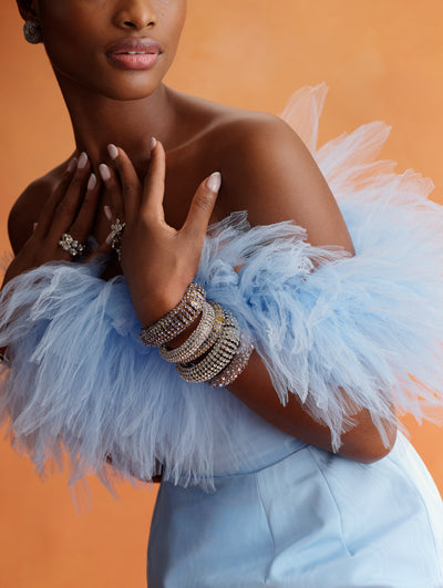 The model is wearing a baby blue top with tulle fringe and matching pants. 