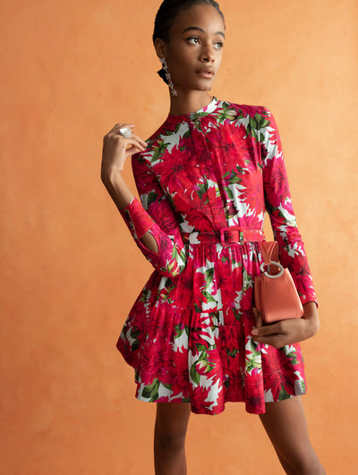 The model is wearing a baby blue mini dress with large pink flowers and a matching belt. 