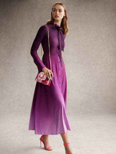 The model is wearing a purple ombre shirt dress with a neck tie detail. 
