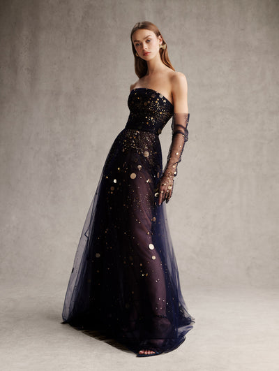 The model is wearing a navy tulle strapless dress with gold applique and matching navy tulle gloves. 