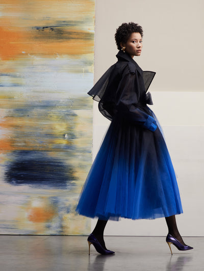 The model poses sideways in an ombre navy tulle coat.