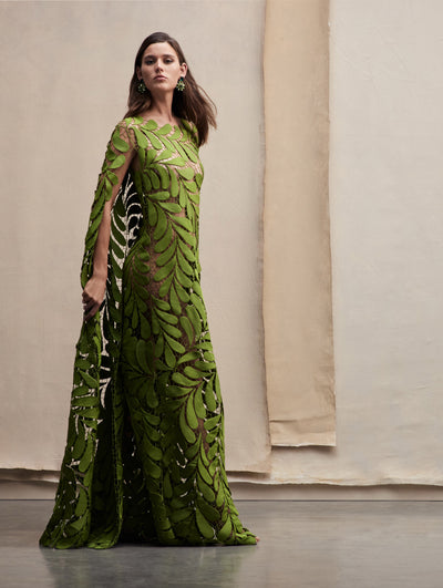 The model poses in a green leave cutout caftan. Side view
