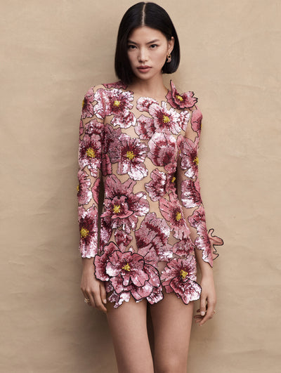 Model wearing a long sleeve mini dress with pink sequin poppies embroidered all around.
