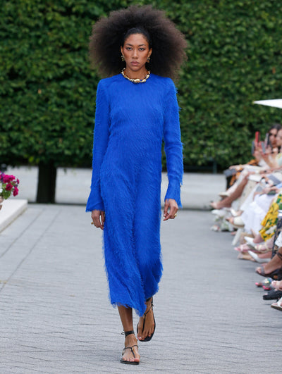 The model is wearing a long sleeve lapis dress in a fringed fil coupé fabric.