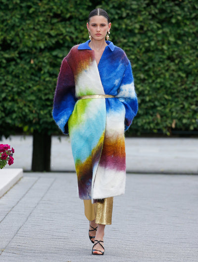 The model is wearing a multicolored coat with a gold belt. 