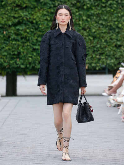 The model is wearing a navy coat with orchid detailing. 