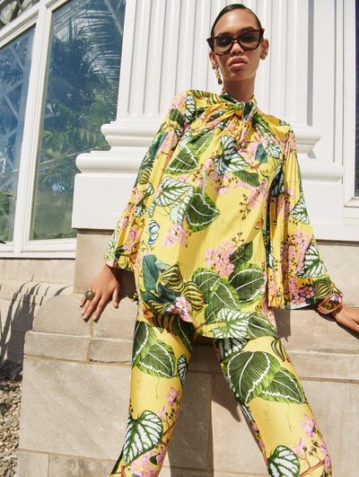A model poses outside in an Oscar de la Renta yellow floral blouse and pant set. 
