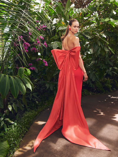 A model poses in a green house in an Oscar de la Renta red bow detail gown. 