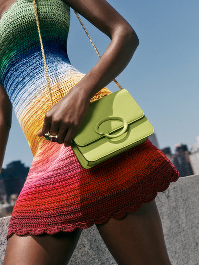 The model is wearing a rainbow crochet knit dress and a classic O flap bag in green. 