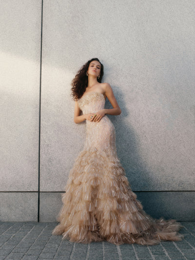 The model is wearing a nude tulle gown and embellished with opulent crystals, fan embroidery degrades down this bustier mermaid gown.