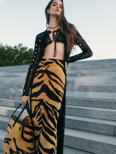 The model is wearing a pencil skirt, cut from chenille tiger jacquard with a black crochet coverup. 