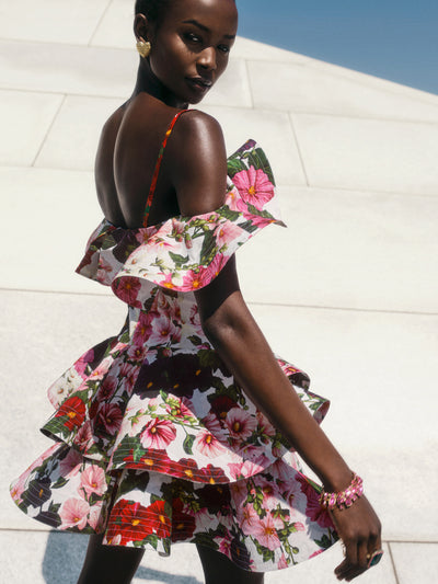 The model is wearing a sculptural mini dress, printed with this season's Hollyhocks motif and defined by voluminous ruffle details at the sleeves and hem