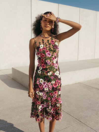 The model is wearing a sleeveless tulle cocktail dress with a feminine full skirt embroidered with hollyhock threadwork. 
