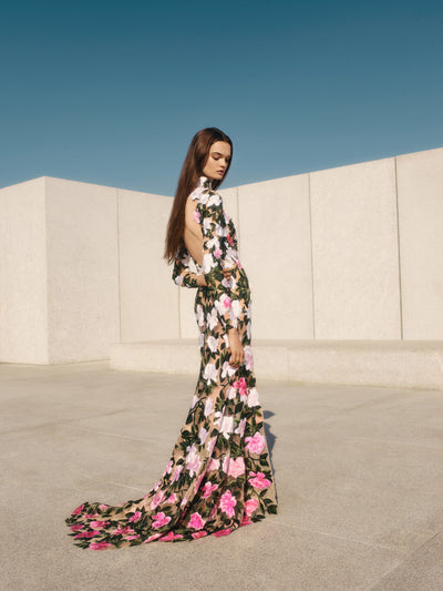 The model is wearing a tulle evening gown with oversized white and pink applique flowers. 