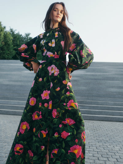 The model is wearing a caftan in this season's camelia print. A button front, self-tie belt and floor-sweeping hemline create effortless elegance.