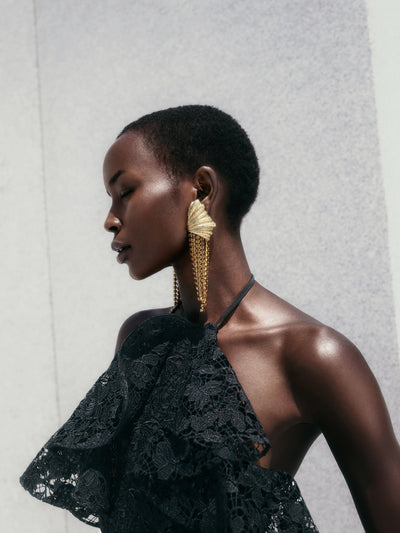 The model is wearing long gold dangling earrings. 