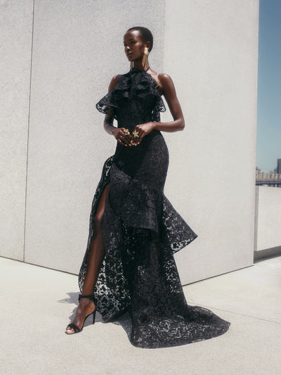 The model is wearing a black lace halter neck evening dress. 