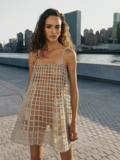 The model is wearing a tulle mini dress adorned with a crystal embellished lattice pattern. 