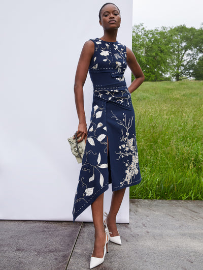 A model wears a blue dress with ivy and twigs embroidered