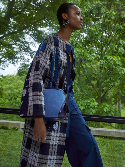 A model wears a tweed printed coat and blue pants