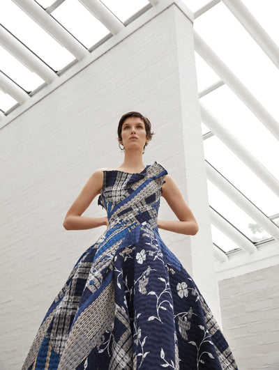 A model wears a quilted gown with shades of blue and embroidered flowers