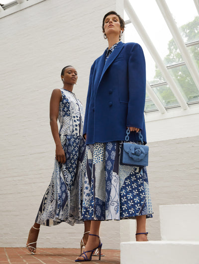 Two models; the model on the left wears a blue and white print dress the model on the right wears the same printed dress with a blue coat