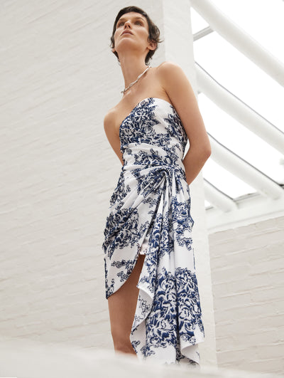 A model wears a white cocktail dress with blue flowers embroidered