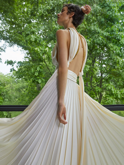 A model wears a a white dress with gold chain details