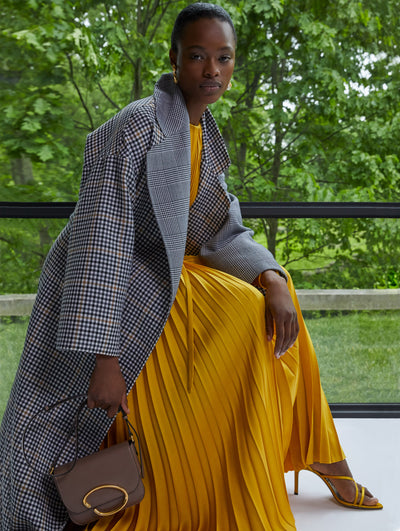 A model wears a black, white and yellow houndstooth coat with a yellow dress