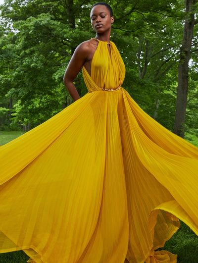 A model wears a yellow gown with gold chain detail