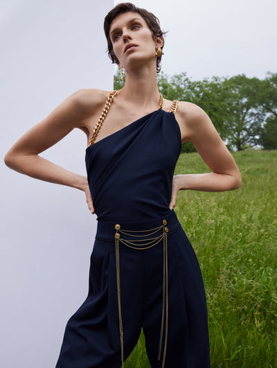 A model wears a black dress and pants with gold details