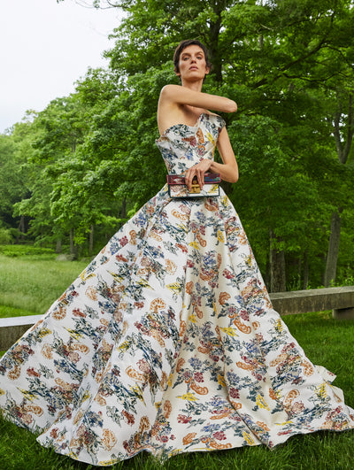 A model wears a gown with yellow orange, blue flower motifs embroidered