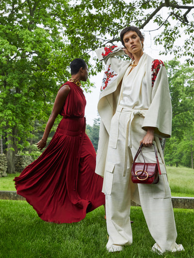 Two models; the model on the left wears a red dress and the model on the right wears a white set with embroidered red flowers