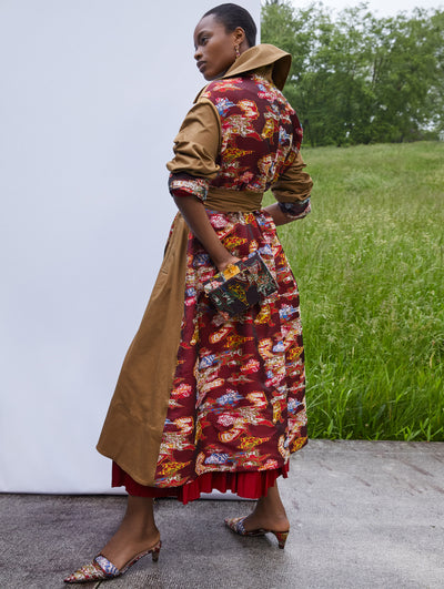 A model wears a trench coat with canvas and red multi print
